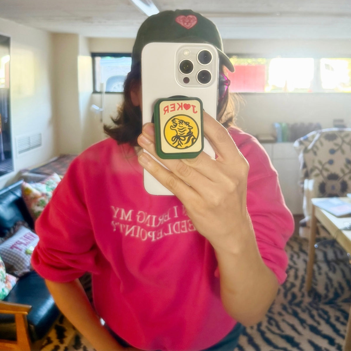 Mirror selfie of a person in a pink sweatshirt holding a phone with the Joker grip on the back