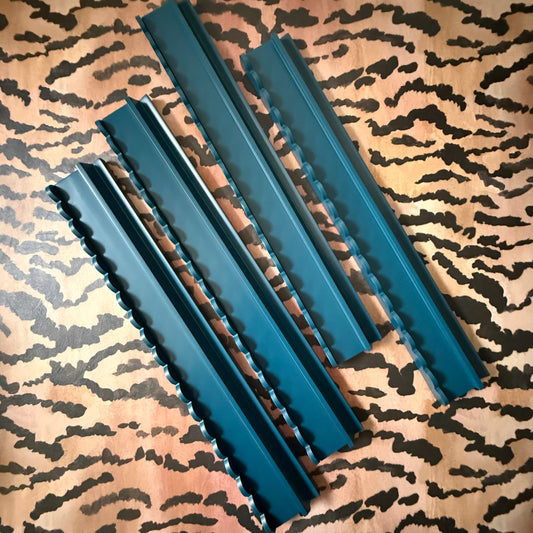 Four marine blue beech wood mahjong racks with scalloped pushers on a tiger-stripe print fabric