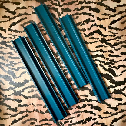 Four marine blue beech wood mahjong racks with straight pushers on a tiger-stripe print fabric
