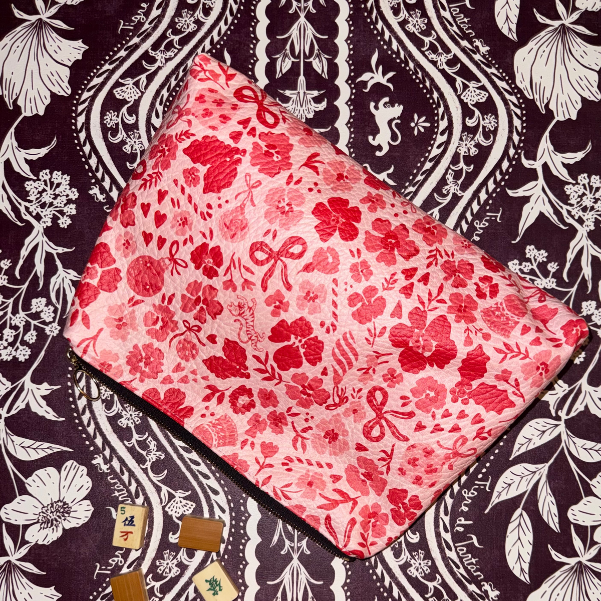 Generous leather pouch in the red and pink Ditsy Christmas MARASCHINO print with mahjong tiles on a dark floral background