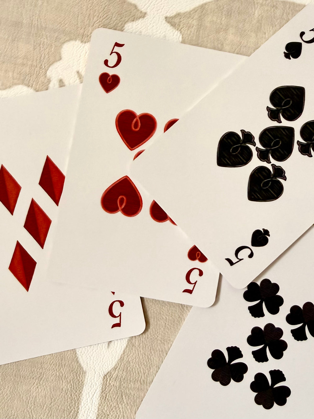 Overlapping fives of diamonds, hearts, spades and clubs with faux-stitched pips from the Jardín de Los Jefes deck