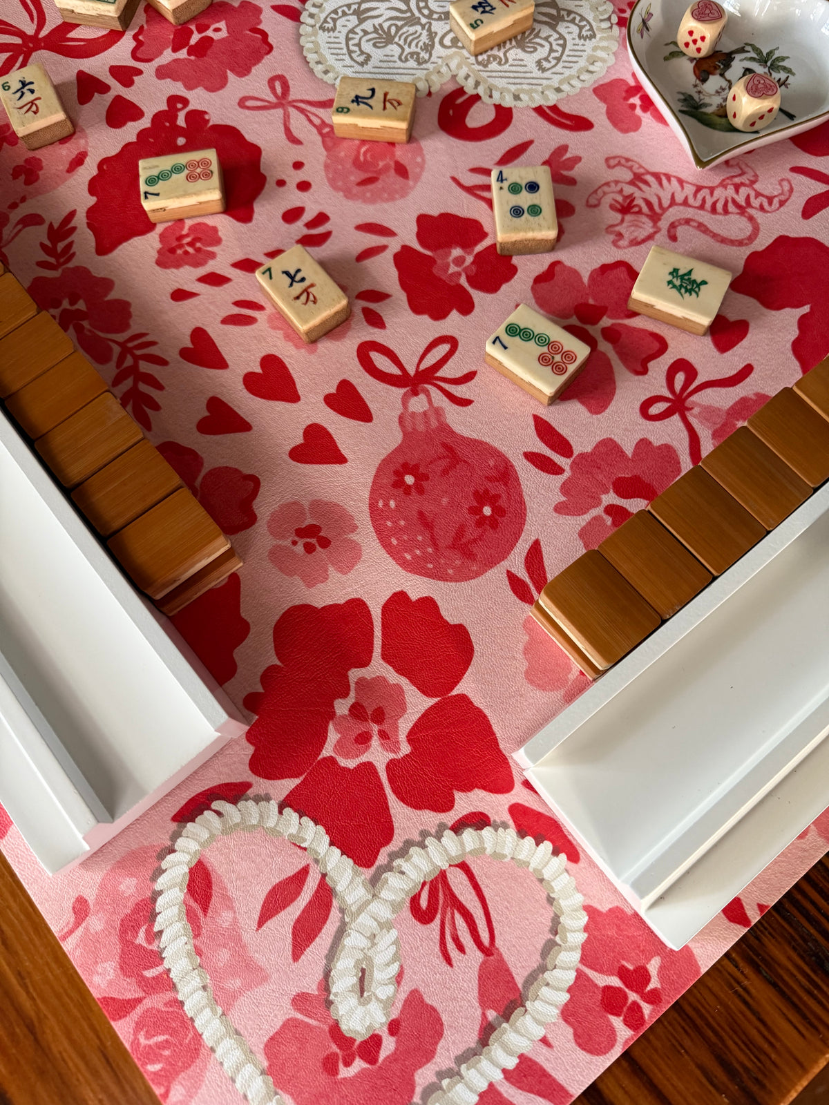 Cream mahjong tiles and wooden racks on the red and pink MARASCHINO mat beside a pearl-beaded heart