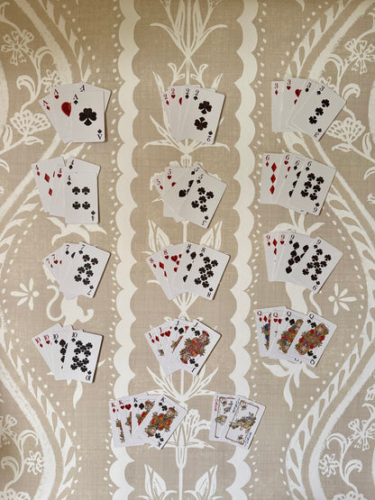 Full deck of Jardín de Los Jefes playing cards fanned out by suit on a linen tablecloth