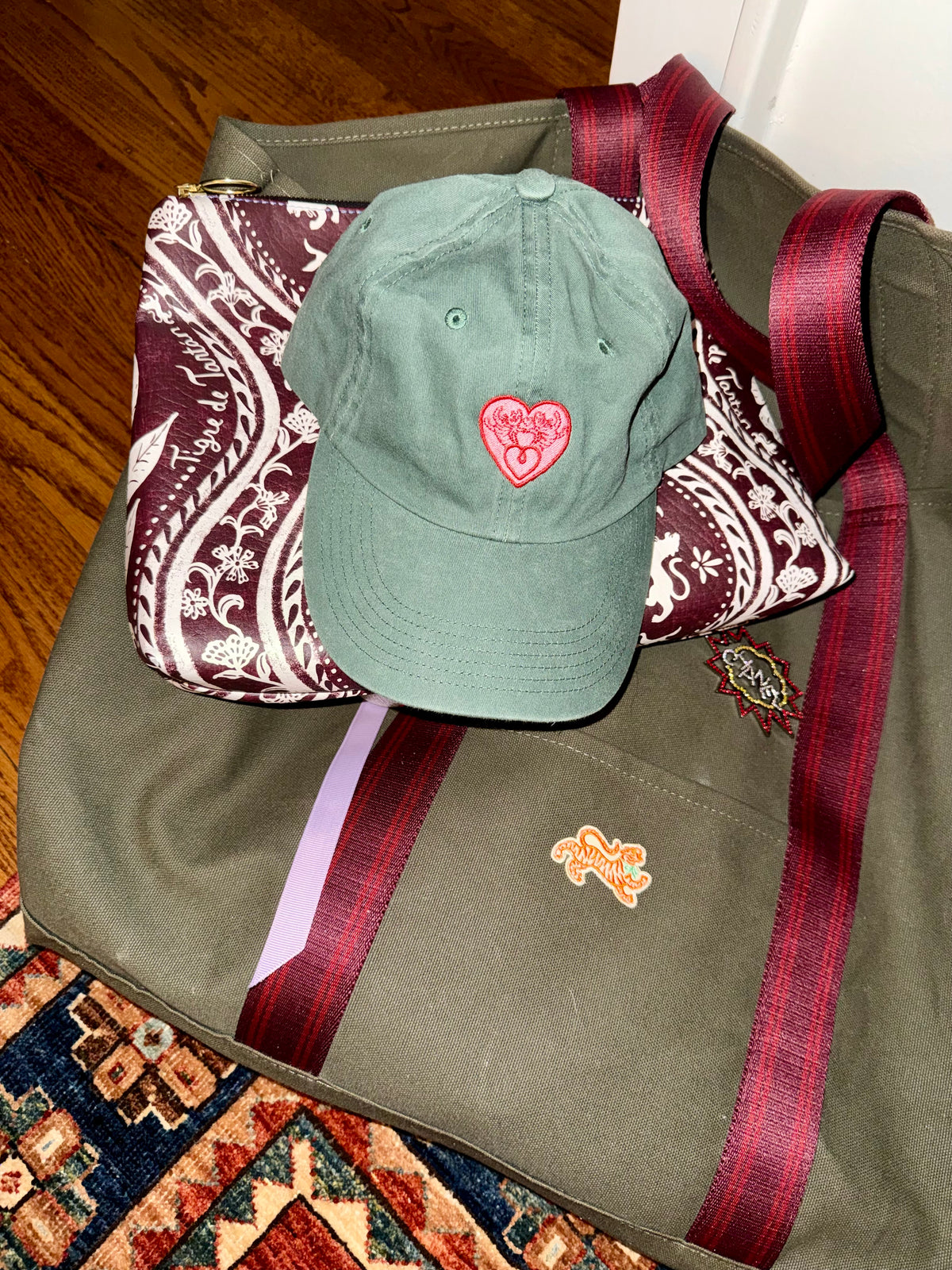 House Hearts cap in hunter green resting on a Tigre de Tartán canvas tote and paisley pouch