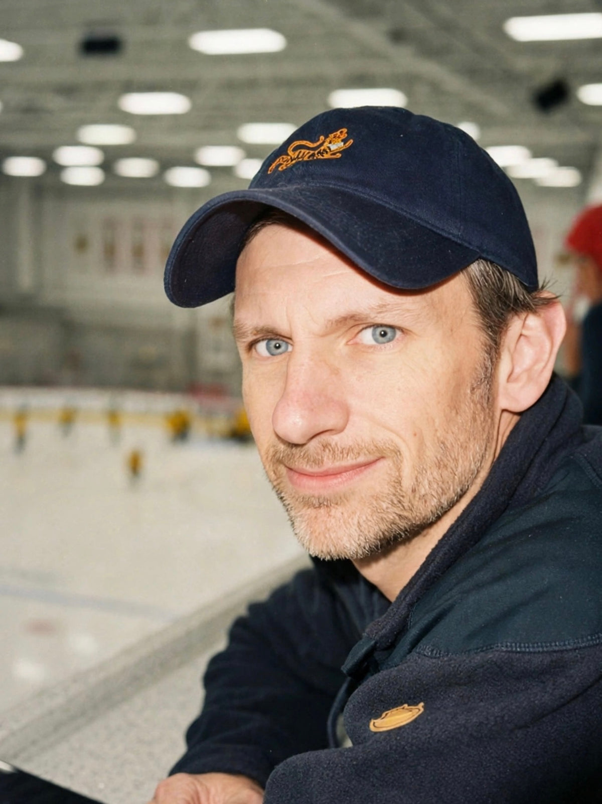 Man wearing the navy logo cap with an embroidered tiger at an ice rink