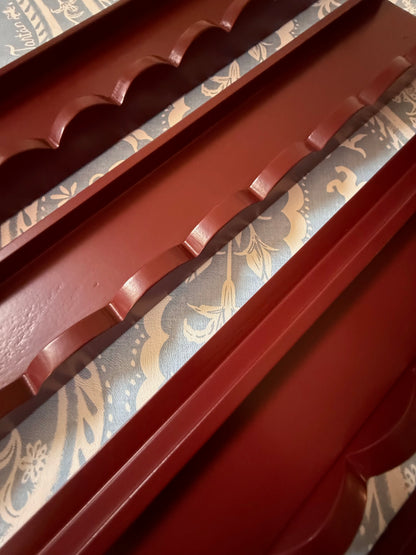 Stack of empty oxblood mahjong racks with scalloped pushers, viewed from above
