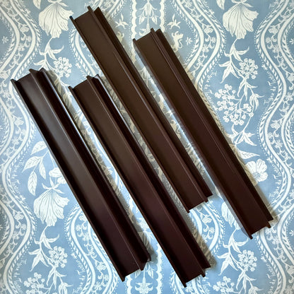 Four rich raisin beech wood mahjong racks with straight pushers on a blue and cream floral fabric