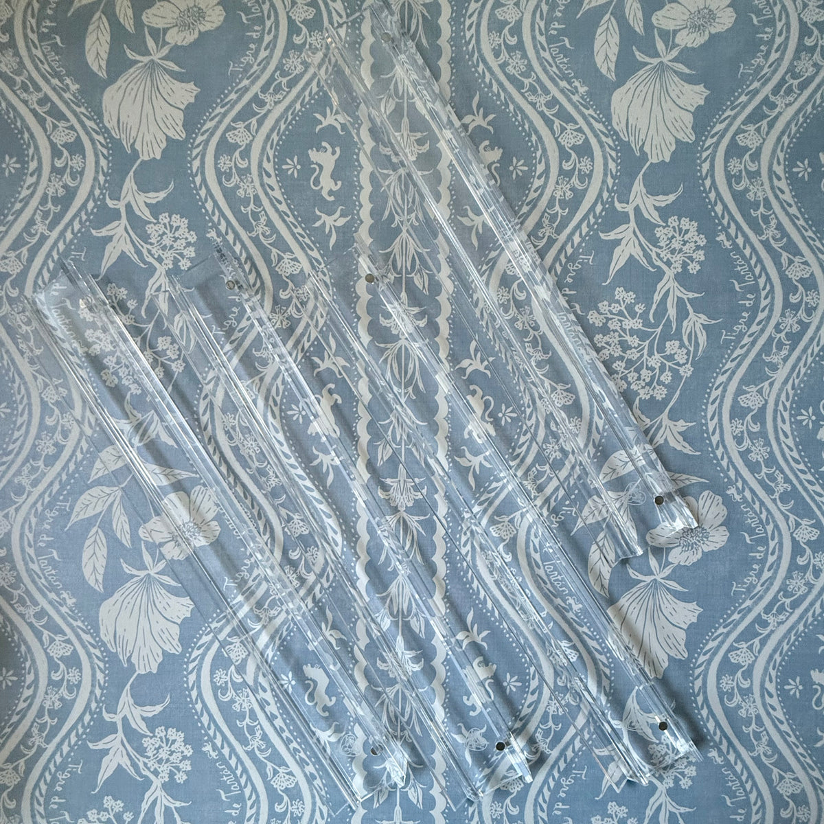 Four clear acrylic logo mahjong racks on a blue and white floral fabric