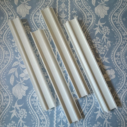 Four dove white beech wood mahjong racks with straight pushers on a blue and white floral fabric