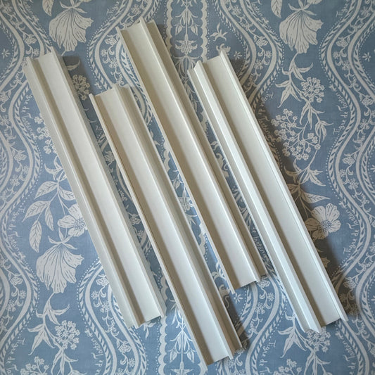 Four dove white beech wood mahjong racks with straight pushers on a blue and white floral fabric