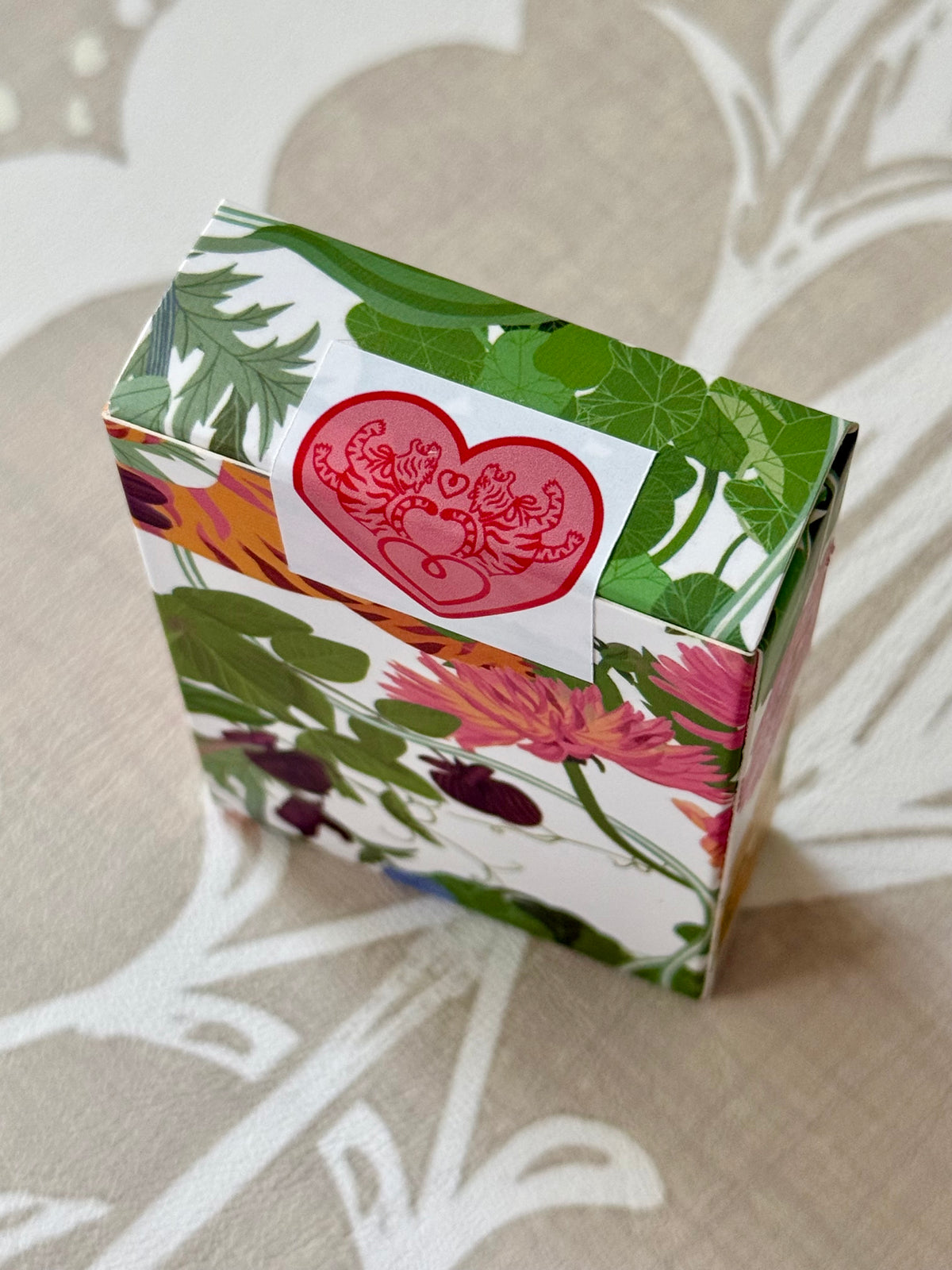 Closed Jardín de Los Jefes gift box in floral tiger print with a red tiger heart seal