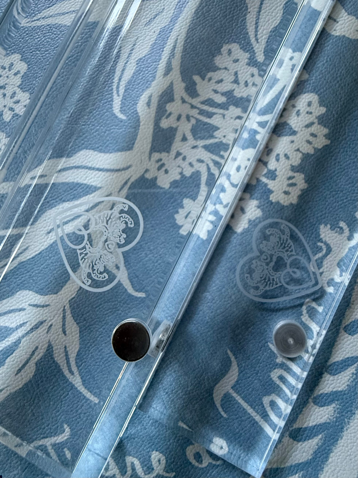 Close-up of the etched heart logo and magnet hole on a clear acrylic rack