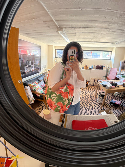 Mirror selfie of a woman carrying a slouchy tote in a green, orange and pink floral print