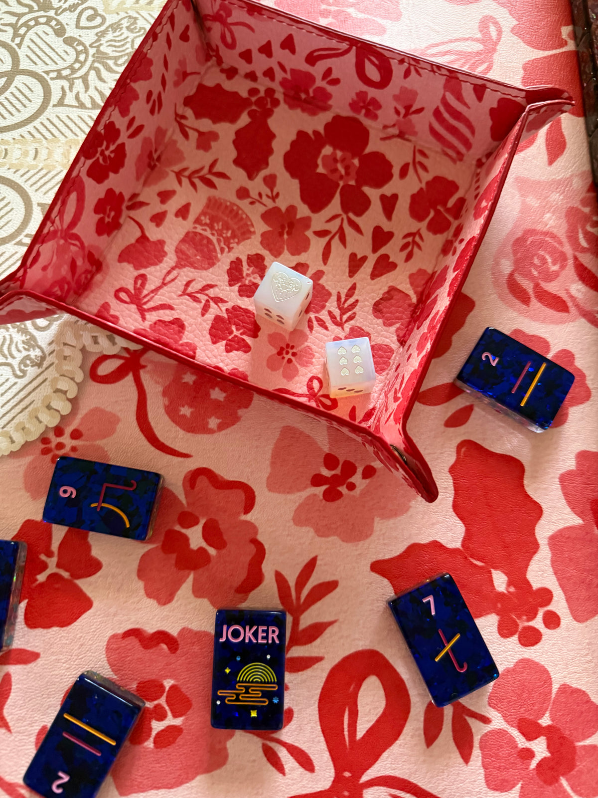 Close-up of the red and pink MARASCHINO snap tray beside navy tiles and a Joker