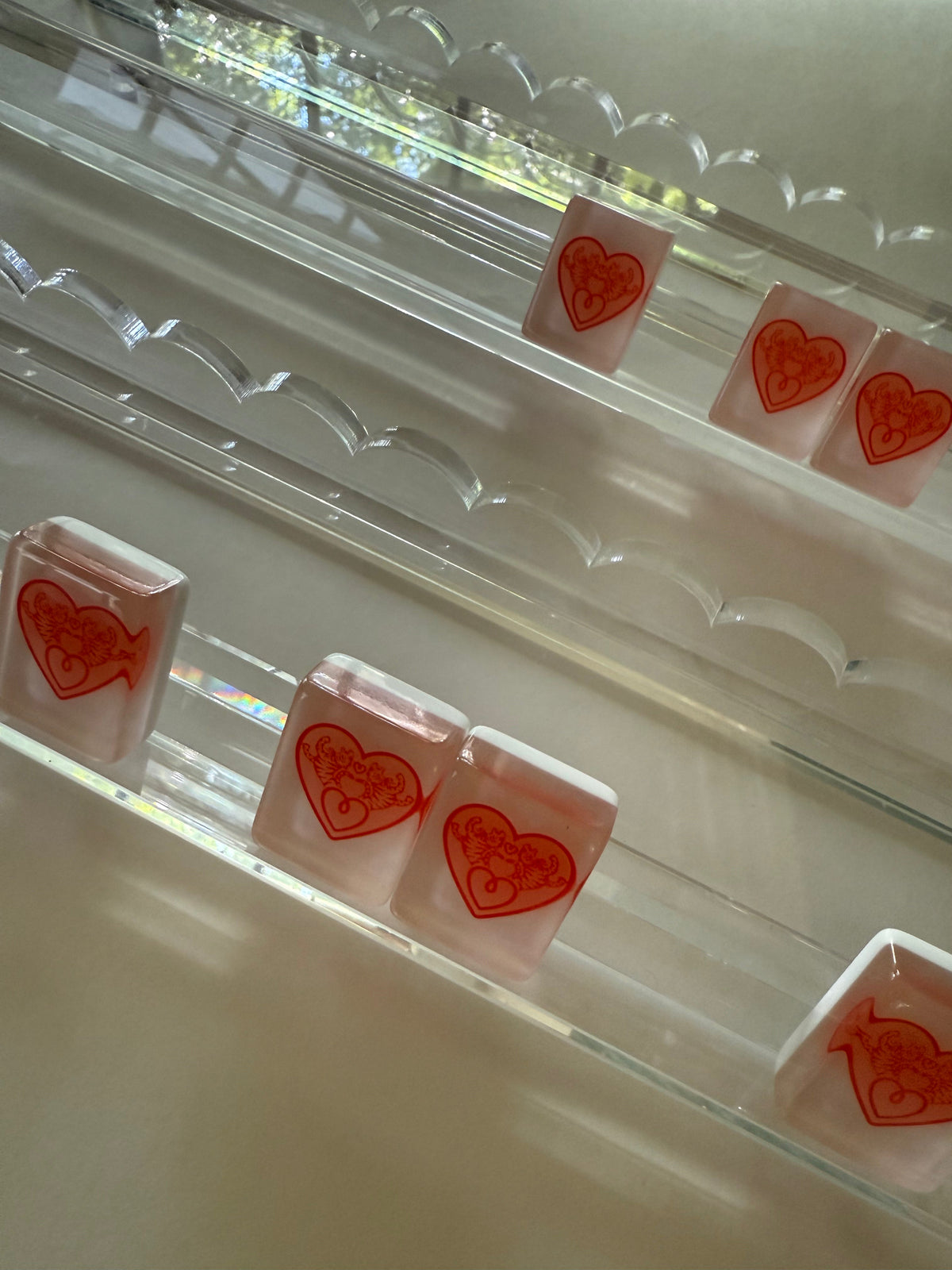 Heart tiles resting in clear scalloped acrylic racks, close-up of the scalloped edge