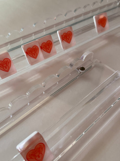 Clear scalloped acrylic mahjong racks with heart tiles, showing the wavy scalloped edge and magnetic pusher
