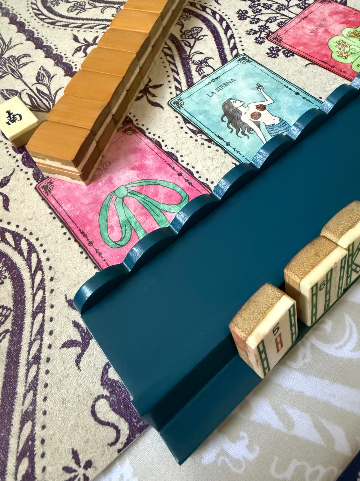 Marine blue scalloped rack with tiles on a purple paisley mat printed with card illustrations