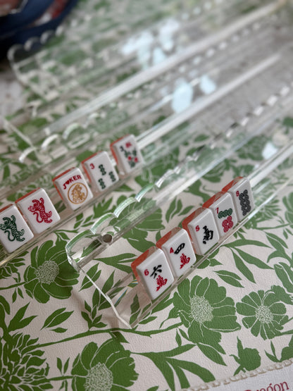 Clear scalloped acrylic racks with tiles on a green floral mat