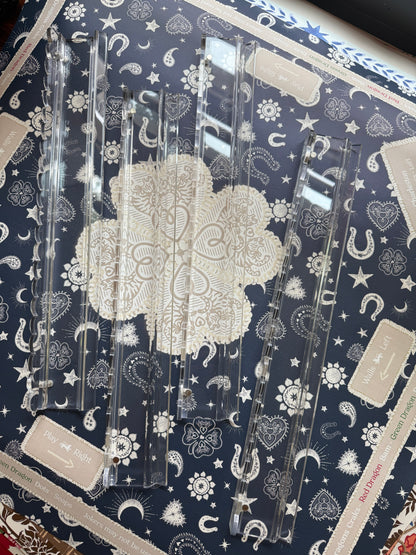 Four empty clear scalloped acrylic racks on a navy bandana-print mahjong mat, seen from above