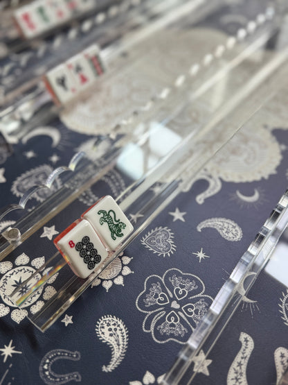 Close-up of tiles in a clear acrylic rack and scalloped pusher on a navy bandana-print mat