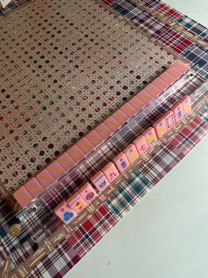 Clear acrylic rack holding pink tiles on a cane-pattern mat with plaid border