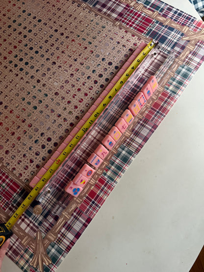 Clear acrylic rack with pink tiles beside a tape measure showing the rack length