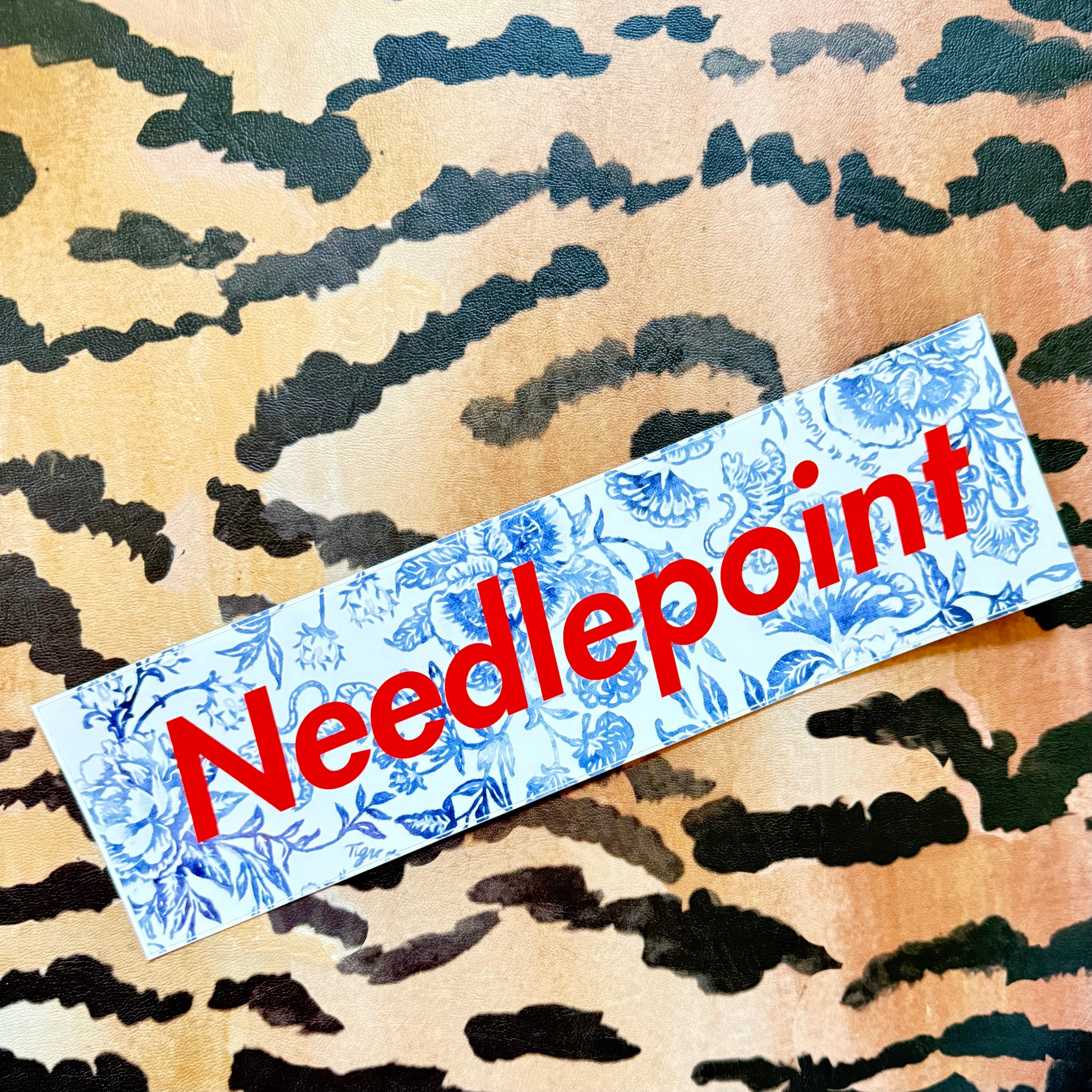 Needlepoint bumper sticker, blue-and-white floral with red lettering
