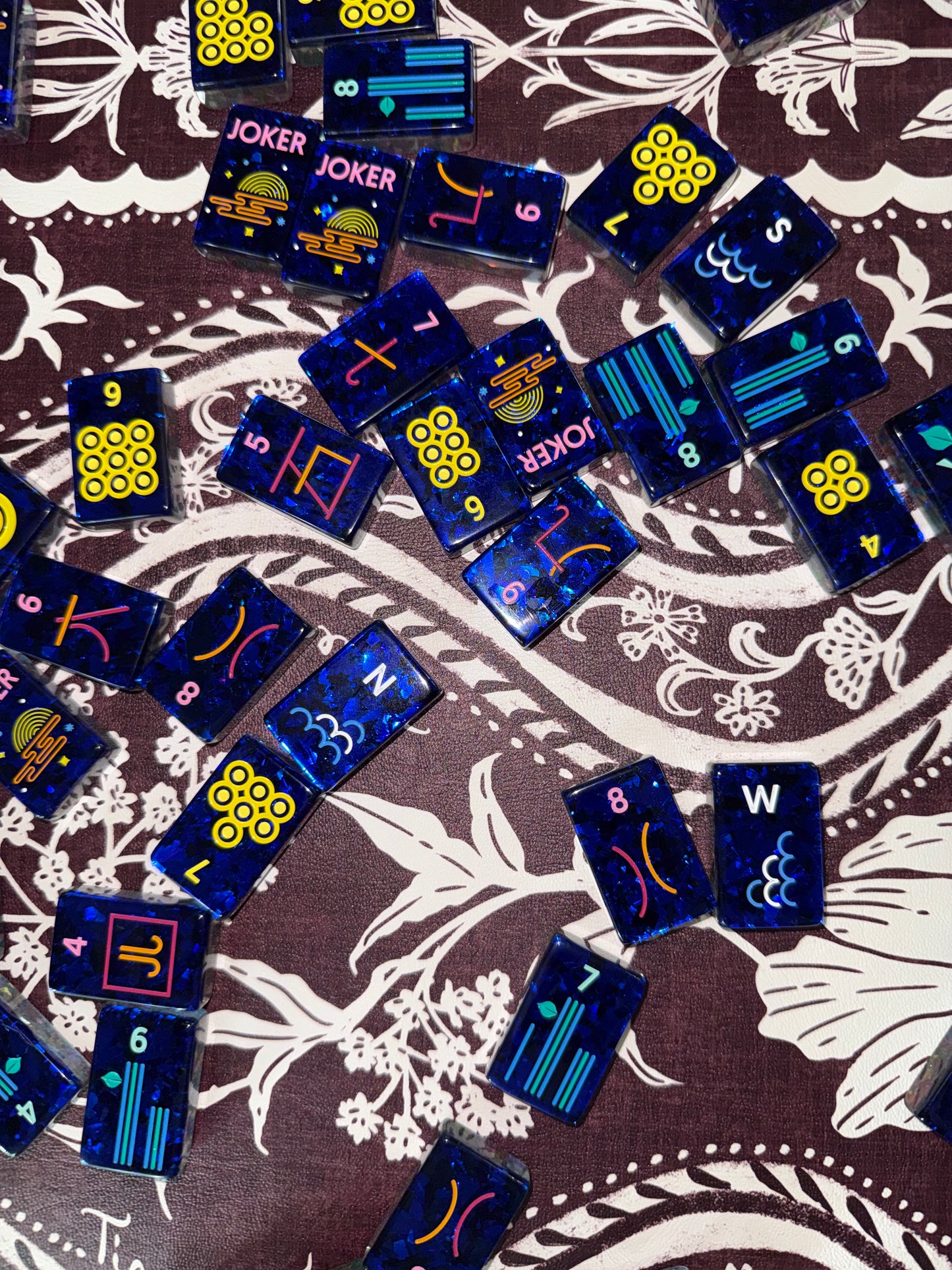 Close-up detail of Mahj Pit Confetti mahjong tiles on a mahjong mat, showing the translucent acrylic and confetti finish