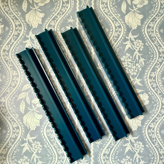 Four marine blue scalloped racks on a blue and cream floral stripe fabric, seen from above