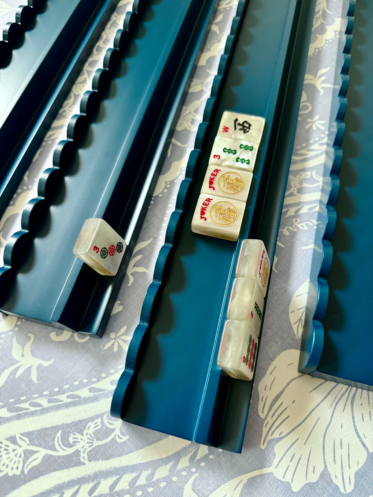 Angled view of a marine blue scalloped rack with cream tiles on floral fabric