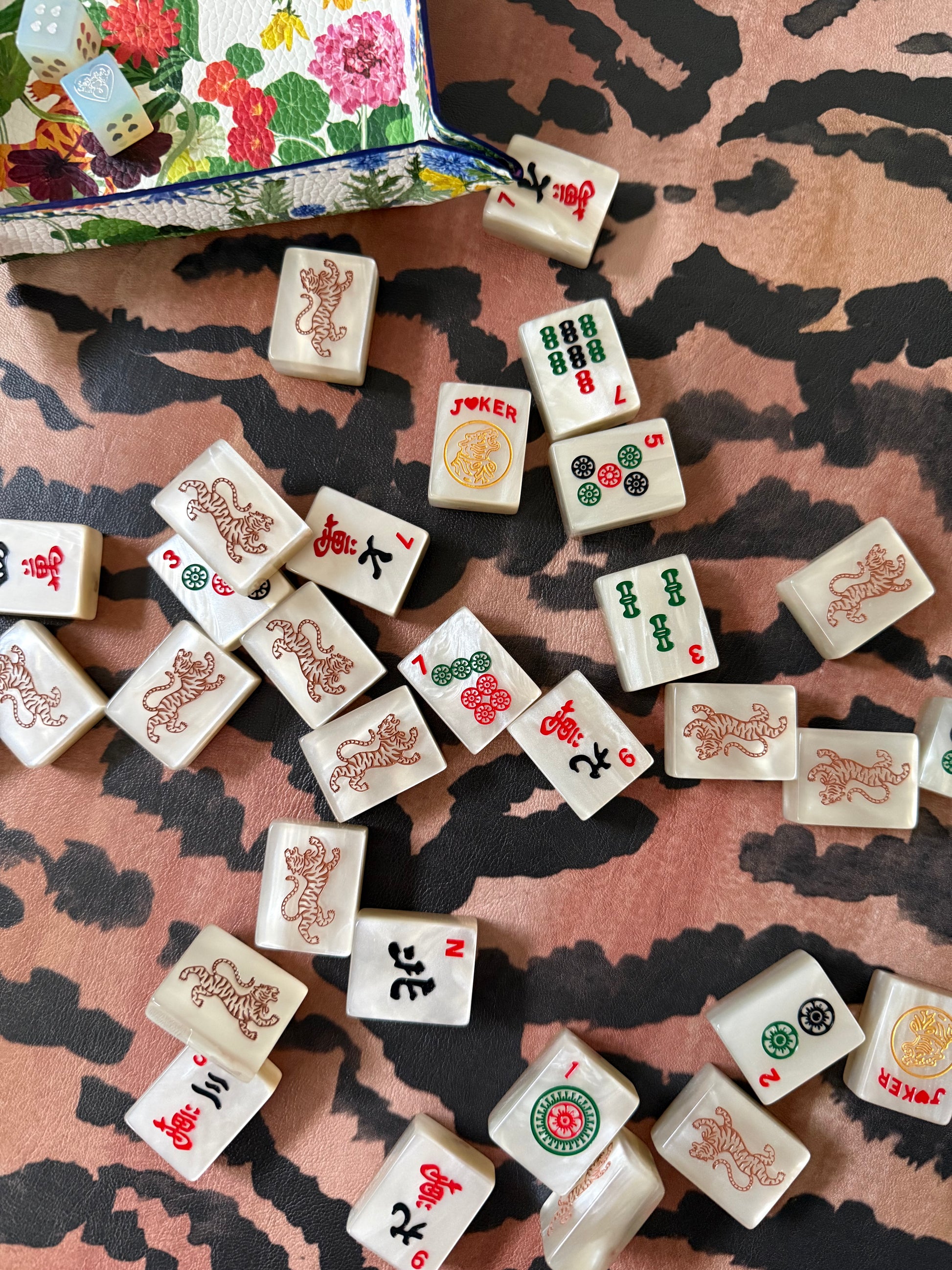 Mahjong tiles spilling from a floral pouch onto the El Tigre tiger stripe mat