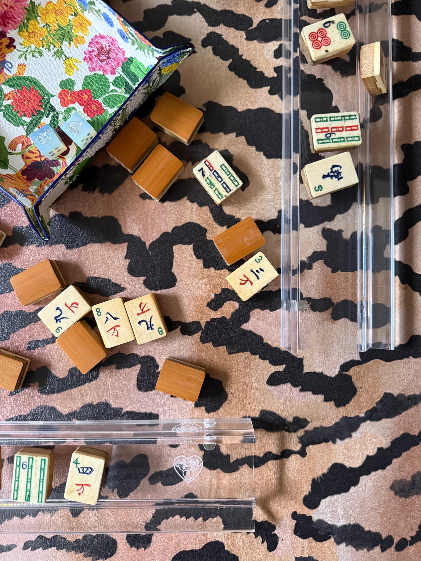 Mahjong tiles, a clear acrylic tile box and a floral pouch on the El Tigre tiger stripe mat