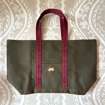 Signature XL Canvas Tote in olive canvas with burgundy striped handles, front pocket and small embroidered tiger patch, laid flat