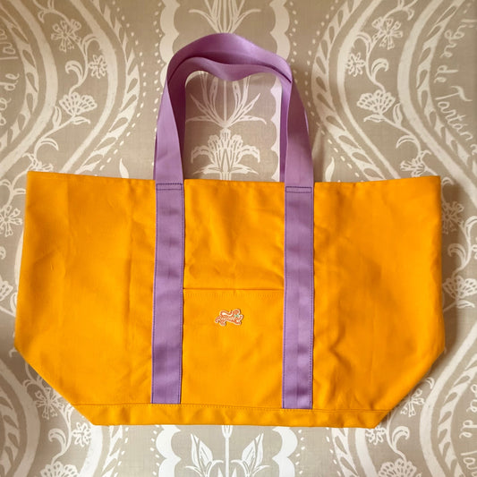 Signature XL Canvas Tote in marigold canvas with lavender handles, front pocket and small embroidered tiger patch, laid flat