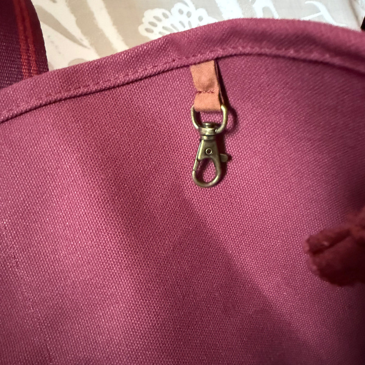 Interior key clip in antique-gold finish on a leather tab inside the oxblood tote