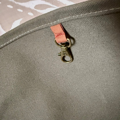 Interior key clip in antique-gold finish on a leather tab inside the olive tote