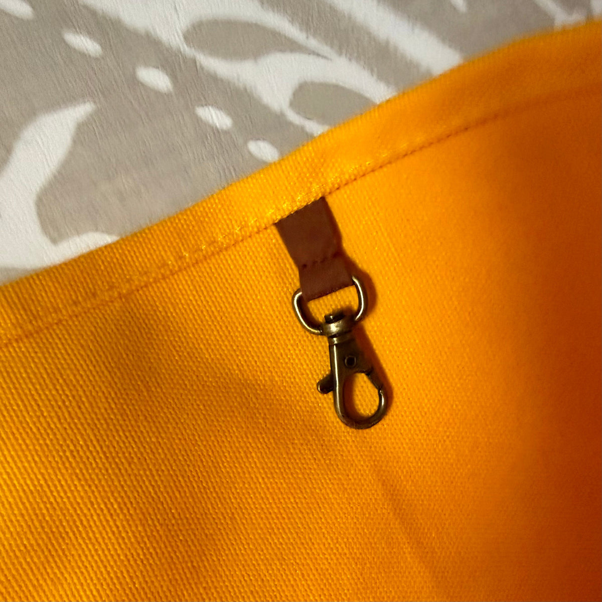 Interior key clip in antique-gold finish on a leather tab inside the marigold tote