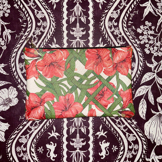 Medium leather pouch in the Estate Sale print, red amaryllis on a green trellis, laid flat on black-and-white damask fabric