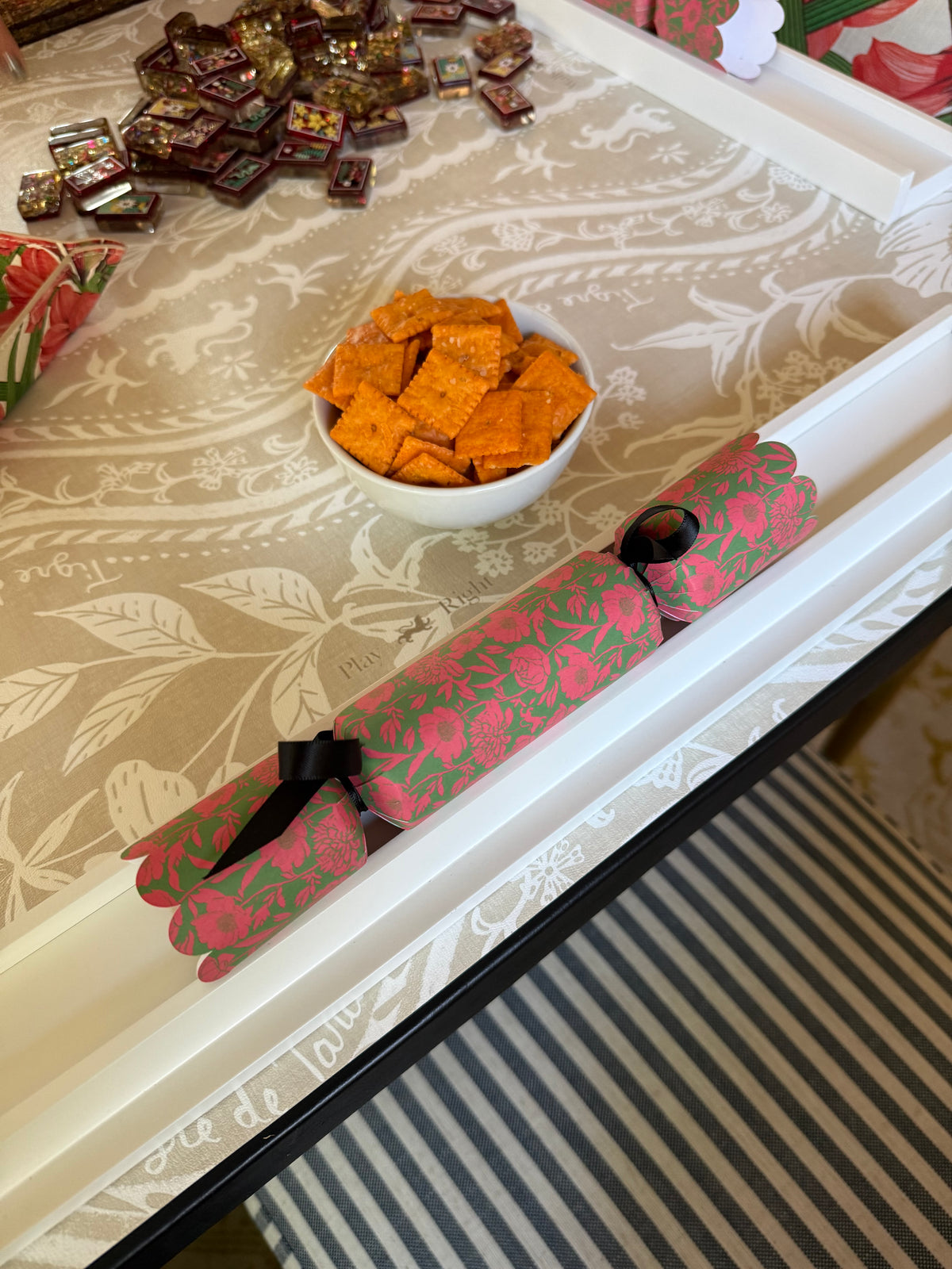 Edge of the Domino Blonde mat with a bowl of cheese crackers, a pink floral pusher and a pile of tiles