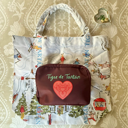 Après Mahj jumbo slouchy tote laid flat with a burgundy Tigre de Tartán zip pouch resting on it, on a patterned tablecloth