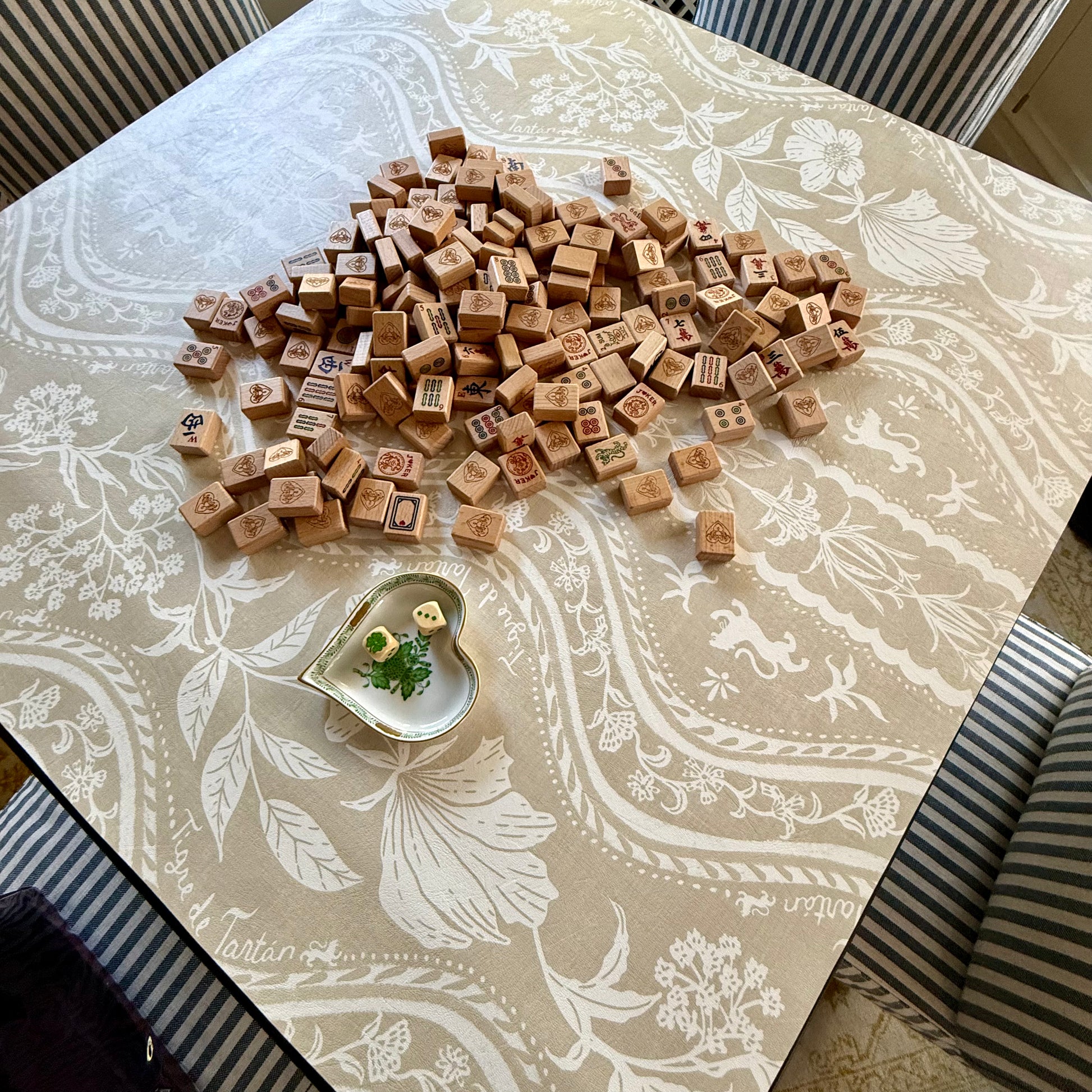 Domino Blonde mahjong mat on a card table with a pile of wooden tiles face down and a heart-shaped dish, from above